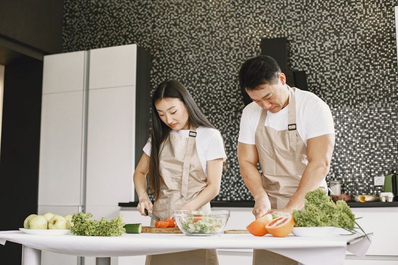 Un couple prépare un repas de légumes frais dans sa cuisine