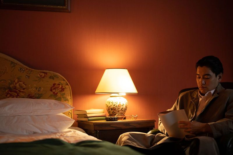 Un homme lit à la lampe, le soir, dans une chambre chaleureuse