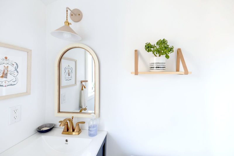 Une salle de bain claire, étagère et miroir