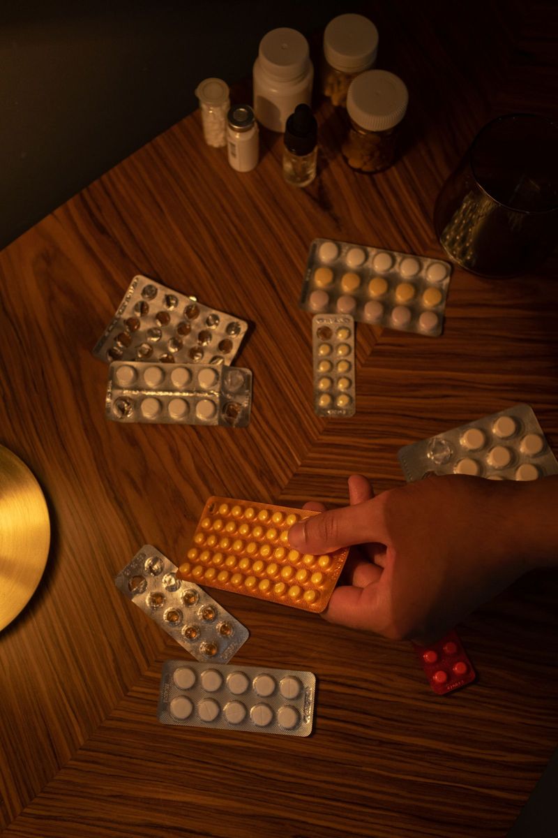 Une main saisit une plaquette parmi des boîtes de médicaments