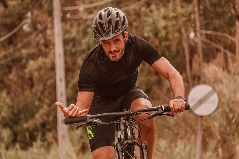 Un homme roule à vélo sur un chemin bordé d’arbres