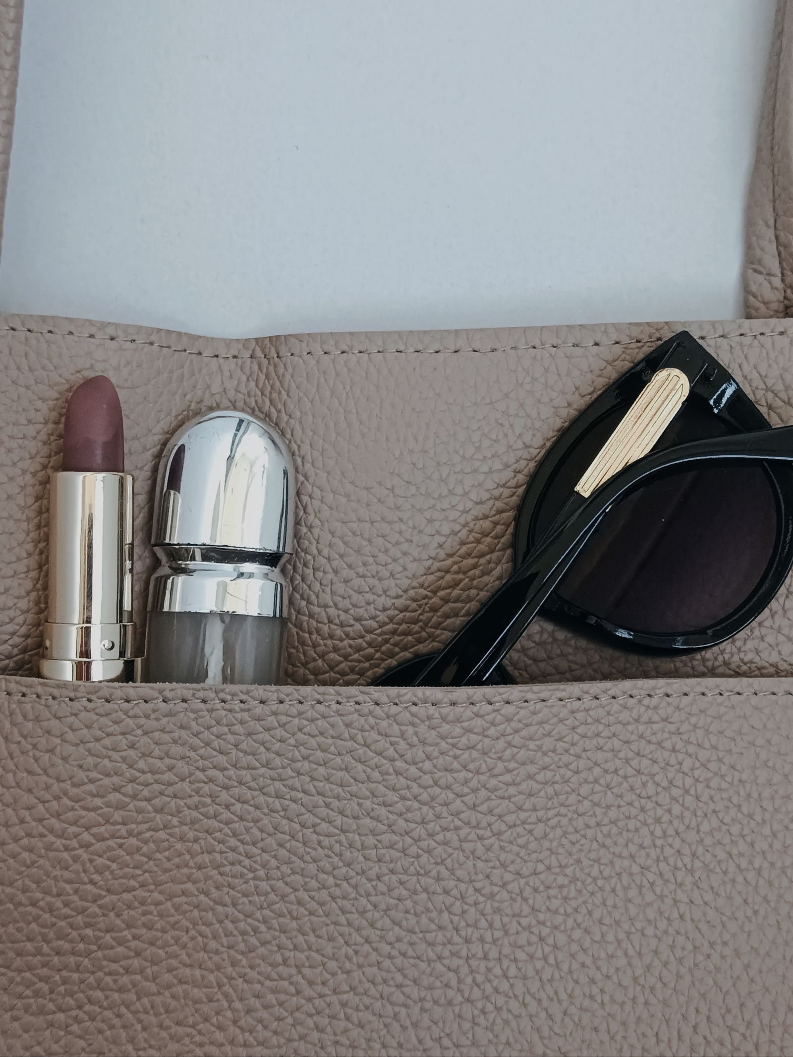 Un sac à main ouvert, plaquette, rouge à lèvres et lunettes de soleil